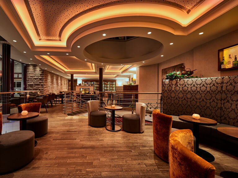 Eine modern eingerichtete Lounge mit großem Bücherregal und gemütlichen Sitzmöglichkeiten und großen Panoramafenstern.