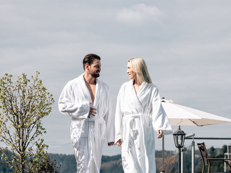 Ein Besucherpaar im Bademantel schlendert durch das Anwesen des Hotels.