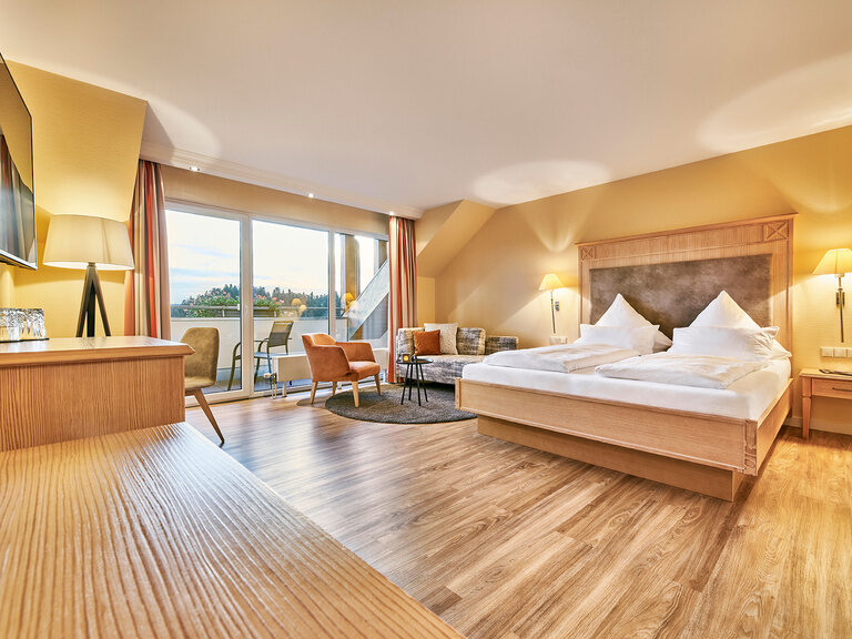 Die Zimmer liegen auf der Südseite im Hotel Kronelamm in den oberen Stockwerken mit Balkon und grandioser Aussicht über den Pool und den Schwarzwald Das edle Deluxe Zimmer Talblick mit Holzboden, schönen Möbeln und toller Aussicht auf den Schwarzwald.