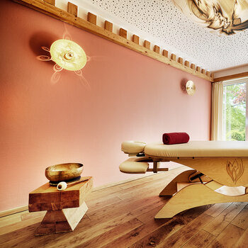 Eine hölzerne Massageliege mit bequemer Auflage steht in einem harmonischen Raum im königSpa des Wellnesshotels Kronelamm Im Schwarzwald.