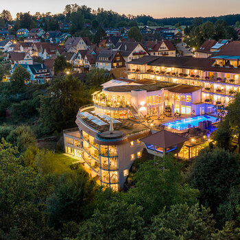 Wellnesshotel Kronelamm im Schwarzwald sowie die Stadt Zavelstein umrahmt von grünen Wäldern.
