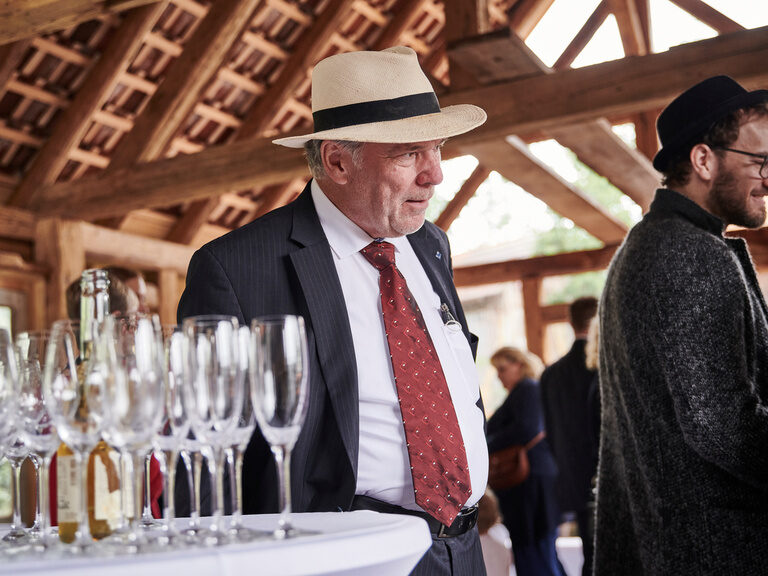 Seniorchef des Hotels Kronelamm, Rolf Berlin, elegant gekleidet bei einem Sektempfang im Theurerhof.