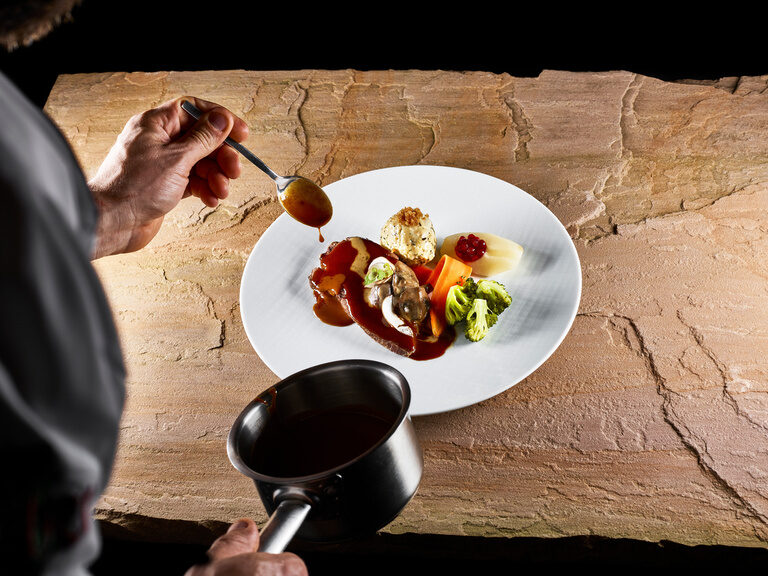 A tasty game dish with homemade bread dumplings is served on a white plate.