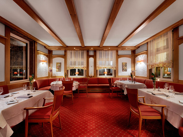 Eine Stube mit eingedeckten Tischen, roten Stühlen und rotem Teppichboden im Gourmetrestaurant Berlins Krone.