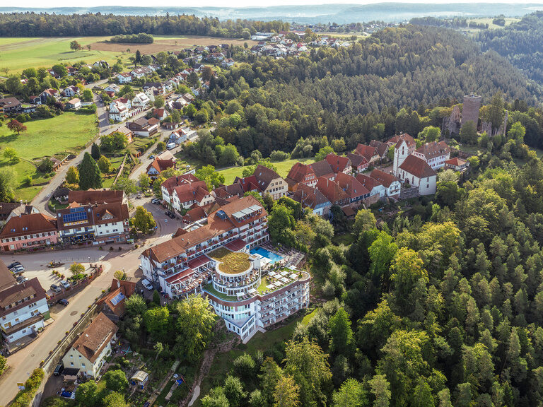 Das 4 Sterne-Superior Hotel eingebettet in den wunderschönen Nordschwarzwald. Das Wellnesshotel Kronelamm im Schwarzwald, ein Teil des Ortes Zavelstein und die Burgruine inmitten den grünen Schwarzwaldes.