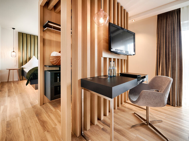 Ein Wohnbereich in der Junuirorsuite Burgherrengemach mit modernen Mobiliar und Holzboden im Hotel Kronelamm im Schwarzwald.