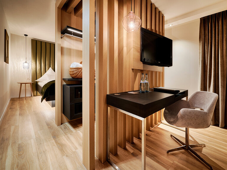 Ein Zimmer, in dem der Wohnbereich durch eine schöne Holzwand vom Schlafbereich getrennt ist.