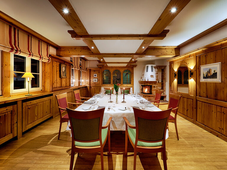 Größere Gruppen können die exzellenten Köstlichkeiten aus der Gourmetküche im Kaminzimmer des Stammhauses Kronelamm genießen. Ein rustikal eingerichteter Raum mit einem Kamin und einer eingedeckten, langen Tafel.