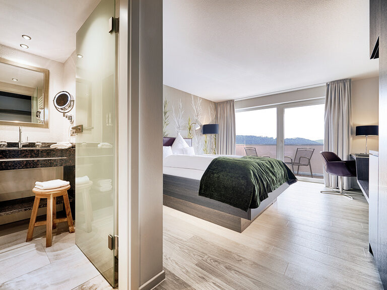 Das Badezimmer in Marmoroptik und der Schlafbereich mit allen Annehmlichkeiten, die ein Hotelzimmer braucht.