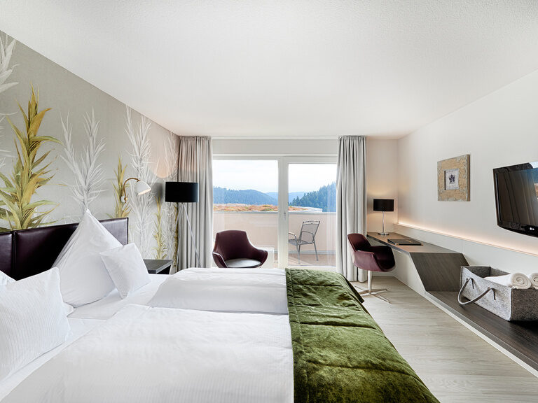 Ein komfortabel eingerichtetes Doppelzimmer mit modischen Möbeln und großen Panoramafenstern.