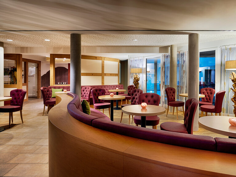 A cozy room with tables and burgundy chairs and benches to relax in.