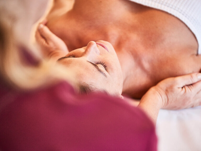 A lady is having her shoulders massaged while lying down by a SPA employee.