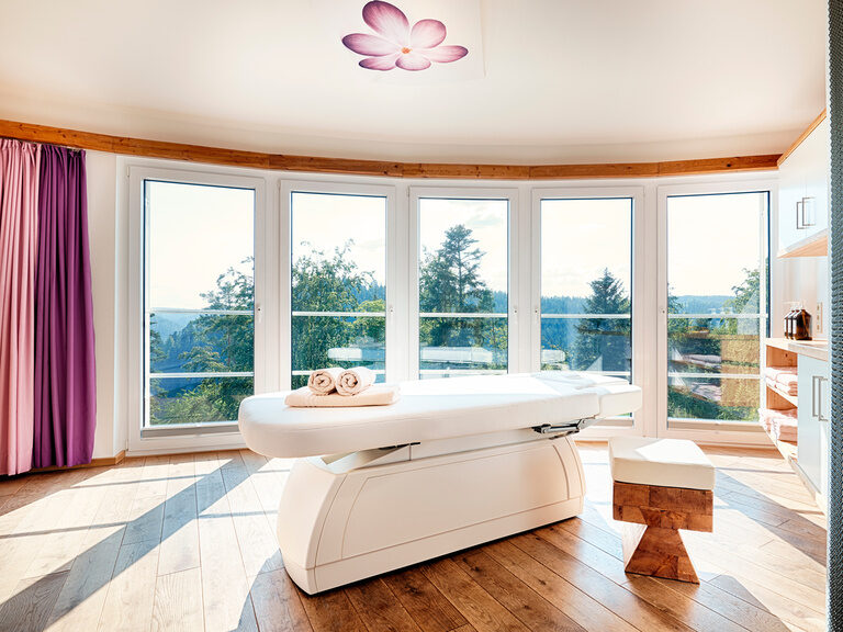 A massage table is in a spacious room with large panoramic windows.