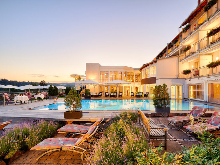 Outdoor pool with sun loungers and part of the wellness hotel.