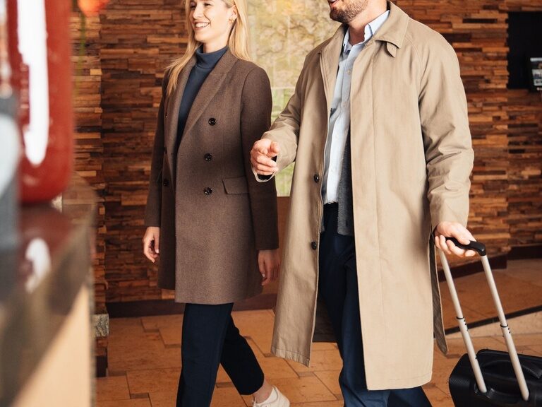 Ein junges Paar mit Koffern Checkt in der Rezeptions des Wellnesshotels Kronelamm im Schwarzwald ein