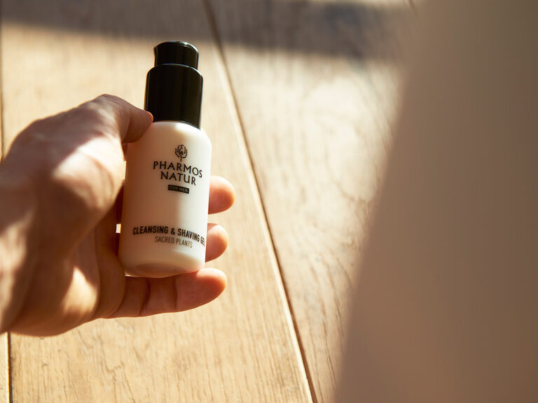 Eine Hand hält ein Produkt der Marke Pharmos Natur.