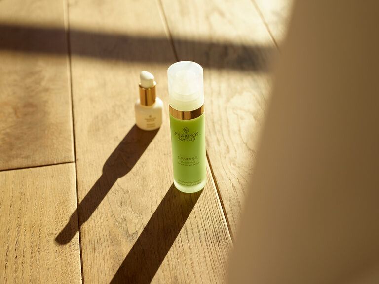 Das Wellnesshotel Kronelamm im Nordschwarzwald arbeitet, der Philosophie entsprechend, ausschließlich mit nachhaltigen Kosmetikmarken. Zwei Produkte der nachhaltigen Marke Pharmos Natur stehen auf einem Holzboden.