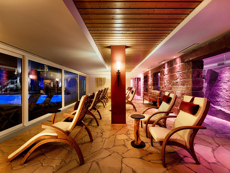 Cozy lounge chairs that offer a view of the outdoor area of the wellness area through a large window wall.