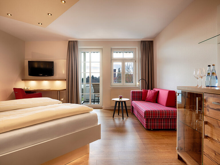 Modernly furnished double room with wooden floors, double bed with high mattresses and comfortable seating.