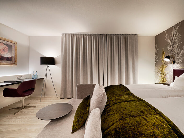 A modern hotel room with closed curtains, romantically lit with lights at night.