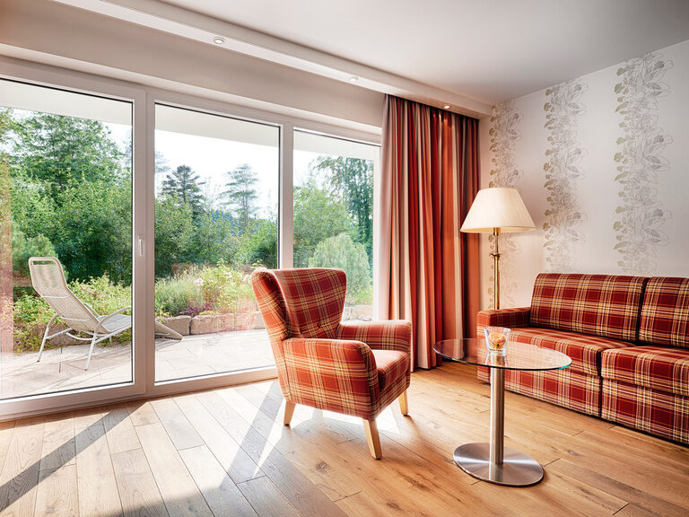 The sun's rays illuminate the seating in warm colors through large panoramic windows.