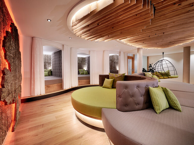 Room decorated in green and gray with cozy niches and a large lying area with cushions.