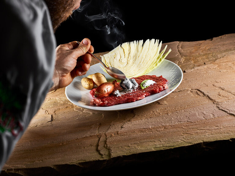Regionalität, Qualität, Herkunft und schonender Umgang mit Lebensmitteln sind in den Küchen des Hotels eine Selbstverständlichkeit. Auf einem Teller liegen ein Stück geklopftes Rindfleisch mit Kartoffeln, Weißkraut sowie Zwiebeln.