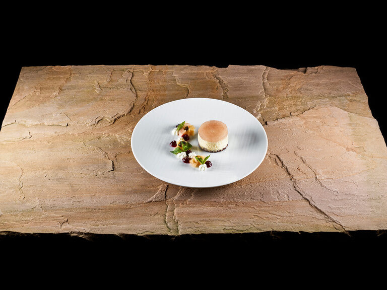 Ein Gericht auf einem weißen Teller steht auf einer Holzplatte.