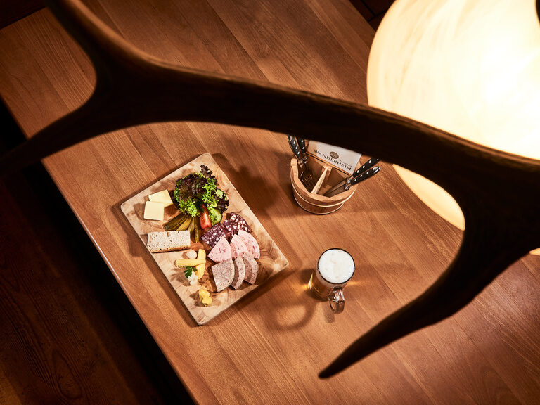 Auf einem Vesperbrett sind verschiedene Wurstsorten, Käse, Salat, Butter und Brot angerichtet.