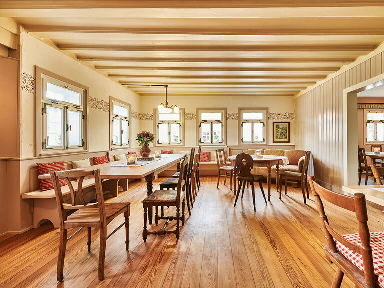 In a large room that resembles a living room, there are various tables with numerous different chairs.