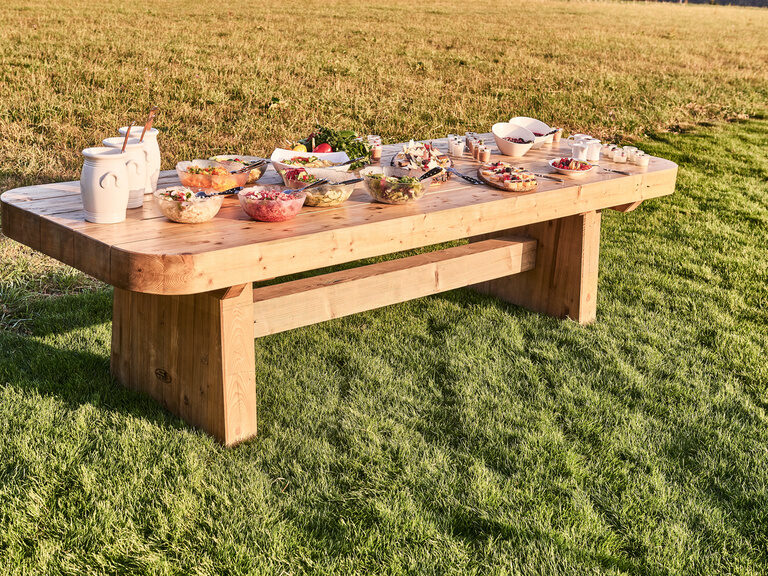 Auf einem großen Biertisch sind verschiedene Speisen, in Form eines Buffets, angerichtet.