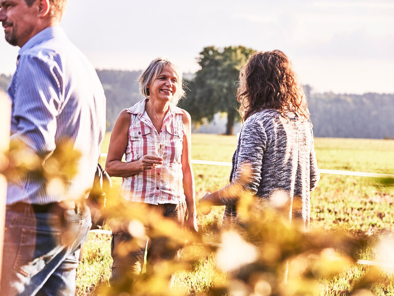 Eine junge Servicemitarbeiterin hält ein Tablett mit Sektgläsern in der Hand und verteilt sie an die herumstehenden Gäste