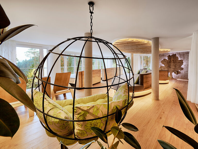 Der Ruheraum Waldreich, mit den vielen Wasserbetten, Hängesesseln und Kuschelnischen, ist der Ort für Zweisamkeit. Ein Hängesessel mit grünen Polstern sowie einige Wasserbetten in einem Ruheraum des königSPA im Hotel Kroneamm im Schwarzwald.