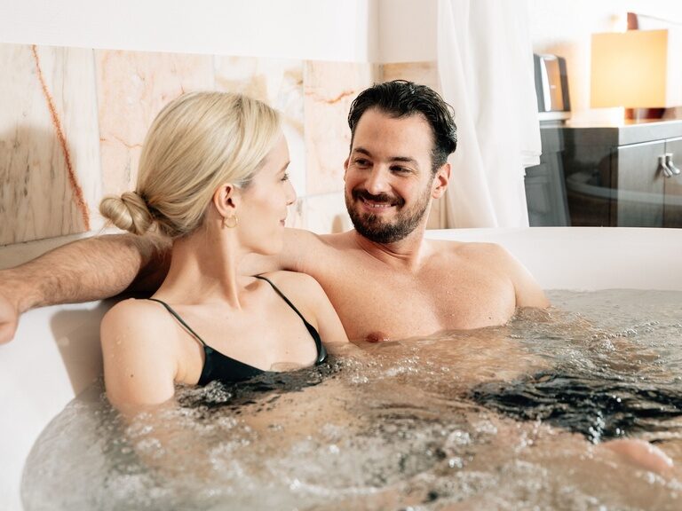 Das Hotel Kronelamm  im Schwarzwald lädt Sie herzlich ein, in einer seiner eleganten Zimmer und Suiten sinnliche Entspannung zu zweit zu genießen. Ein glückliches Paar sitzt gemeinsam im Whirlpool und entspannt sich.